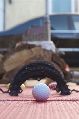 Golfball vor einem halbkreisförmigen Hindernis auf einem roten Untergrund