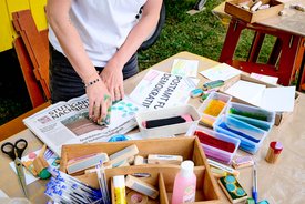 auf einem bunten Basteltisch sind verschiedene Stempel mit Wörtern aus verschiedenen Sprachen zu sehen: FReiheit, Utopie, Gemeinschaft