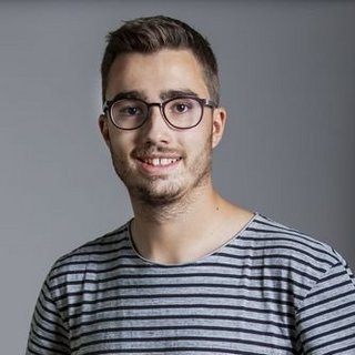 Mann mit kurzem Haar trägt ein gestreiftes T-Shirt und steht vor grauem Hintergrund