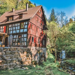 Seitenansicht auf die Klingenmühle, im Hintergrund ein kleiner Bachlauf.