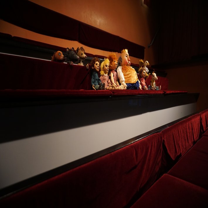 Figuren des Theaters sitzen im Zuschauerraum