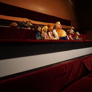 Figuren des Theaters sitzen im Zuschauerraum