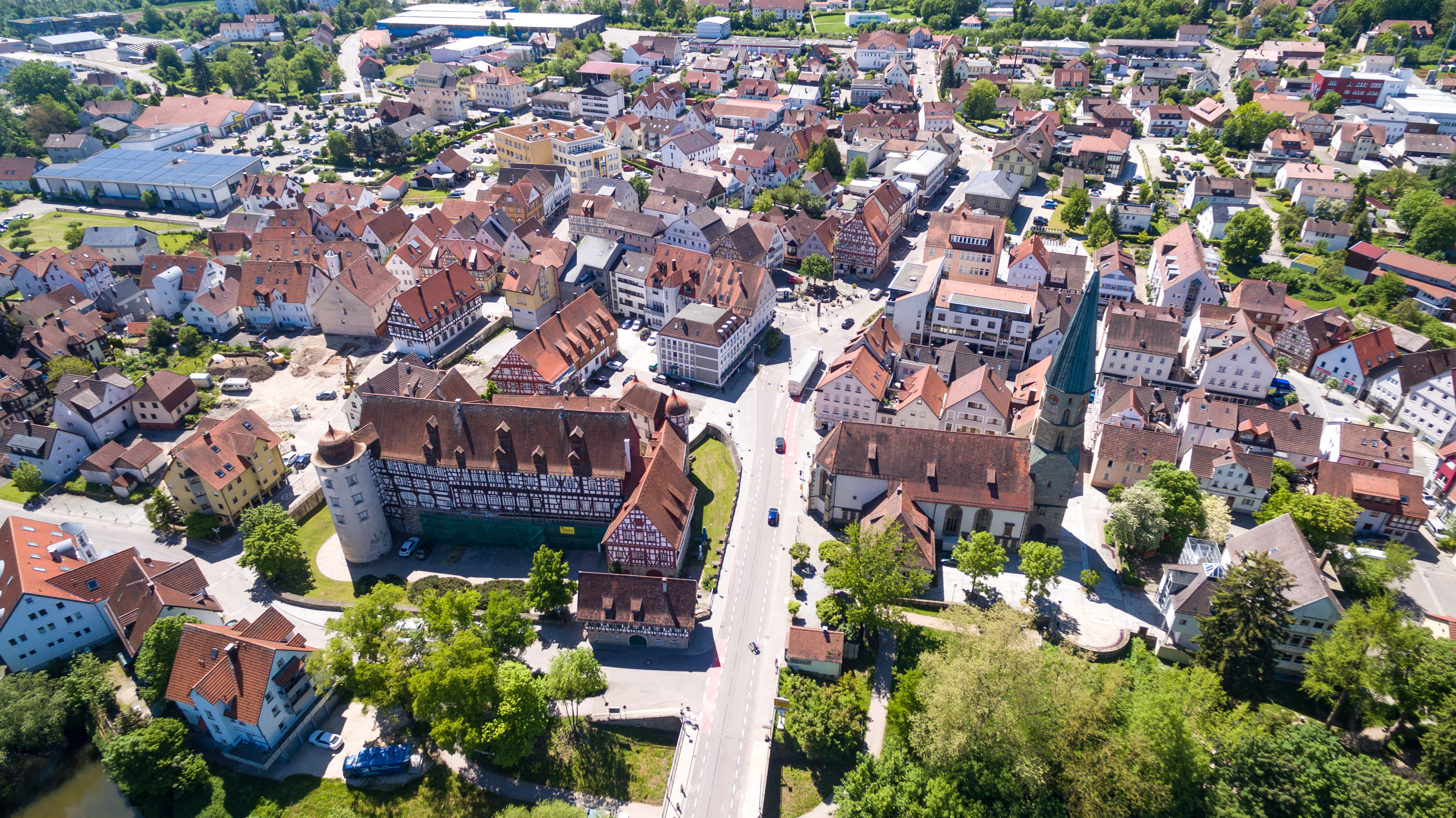 Luftaufnahme der Stadt Gaildorf mit dicht bebautem historischen Zentrum, Fachwerkhäusern und einer großen Burganlage im Vordergrund