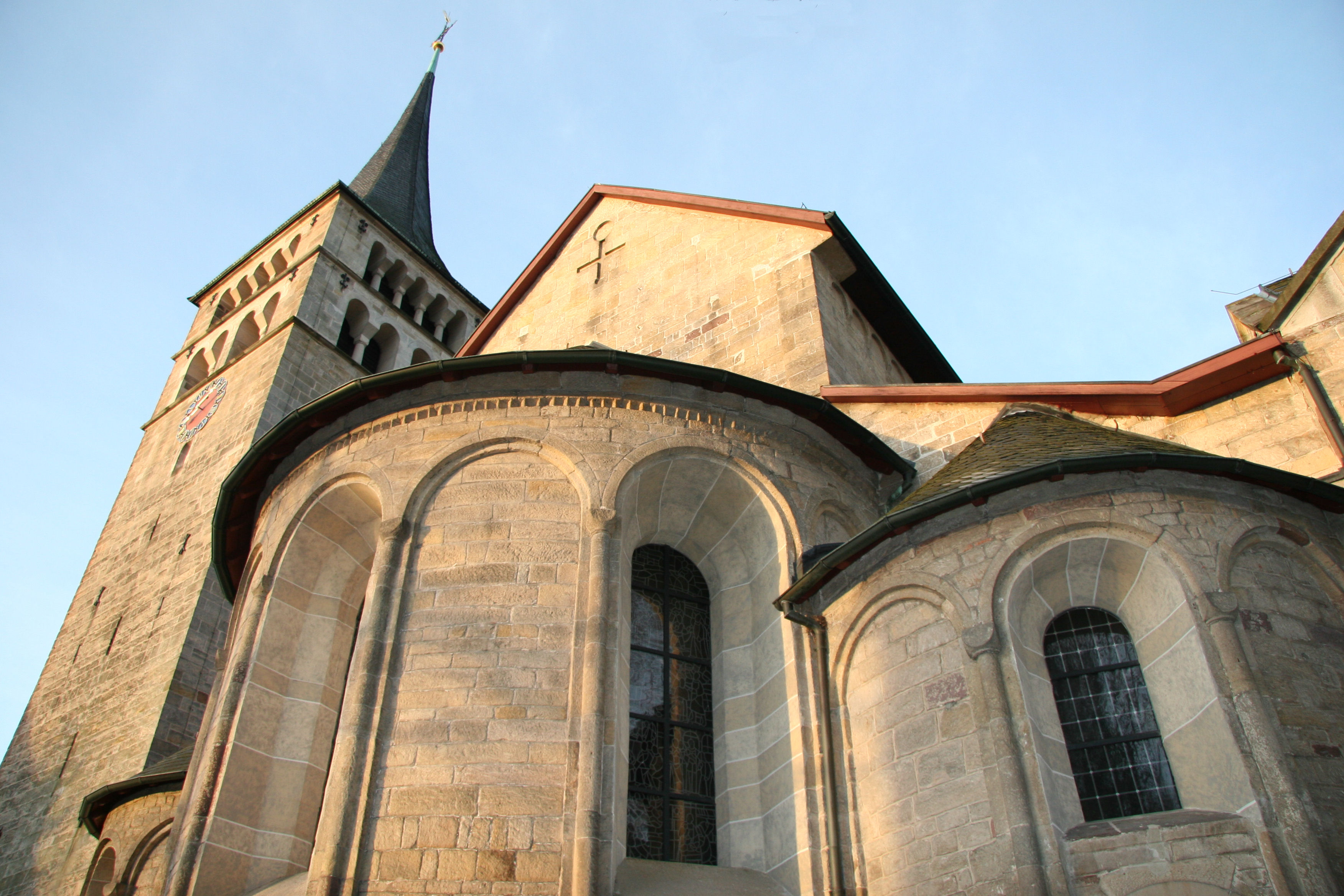 Aussenansicht mit Chor, Apsiden und Turm vor blauem Himmel