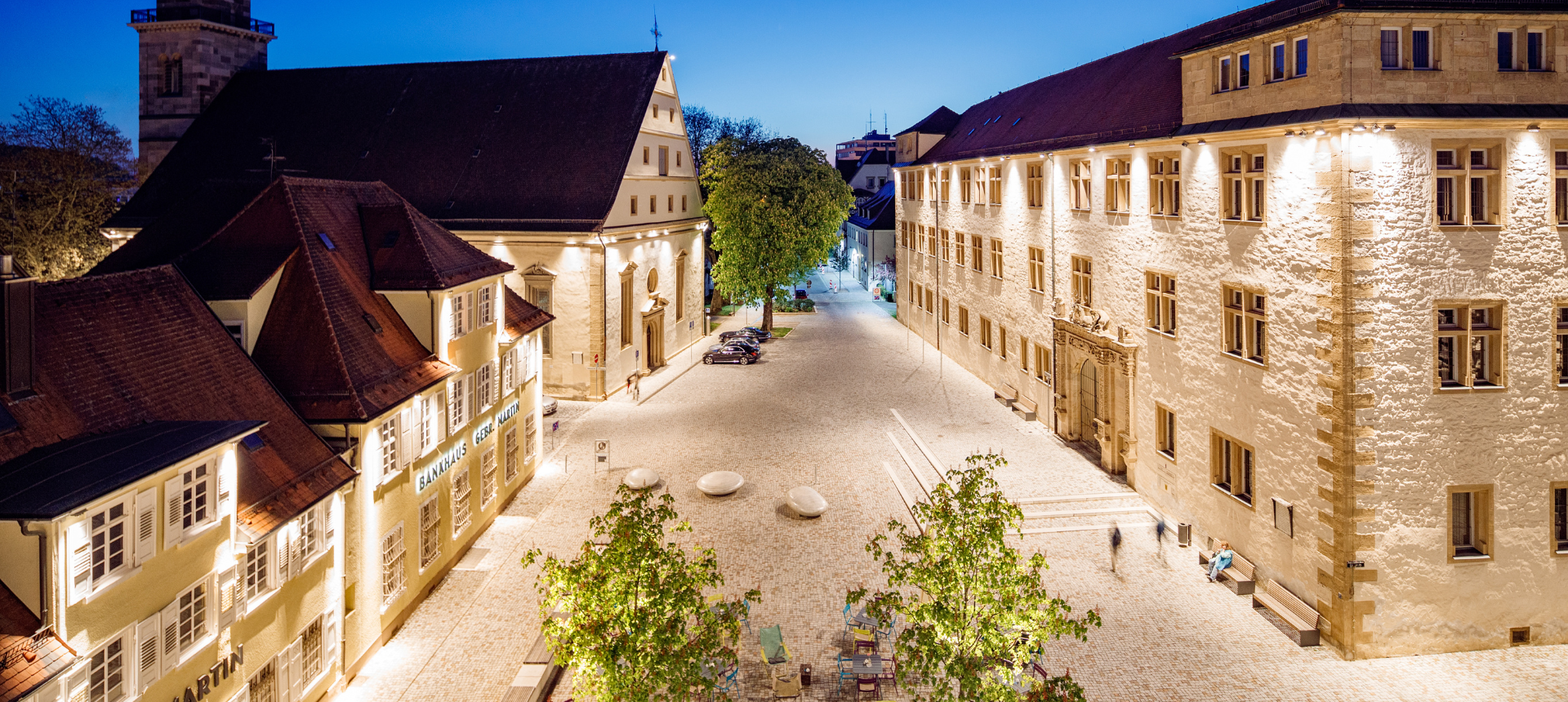 Blick von oben auf den Schlossplatz bei Nacht. Die Gebäuder sind beleuchtet.